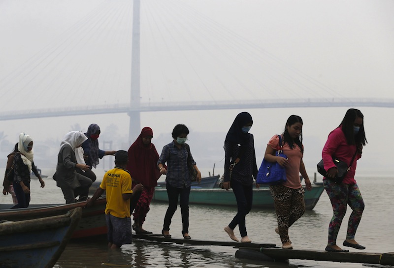 Workers walk on wooden planks as they disembark a boat after crossing Batanghari River in haze-shrouded Jambi, on the Indonesian island of Sumatra, September 17, 2015.u00c2u00a0u00e2u20acu201d Reuters pic