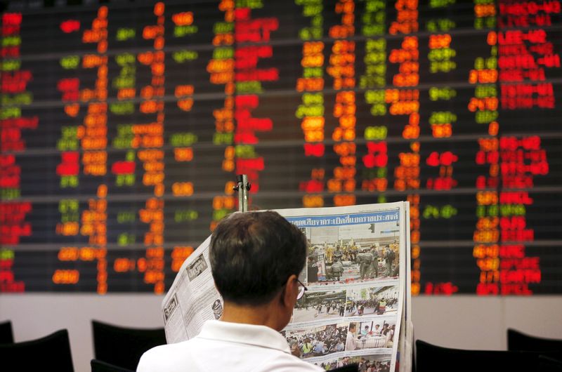 A Thai investor reads a newspaper in front of an electronic board displaying live market data at a stock broker's office in central Bangkok, August 19, 2015. u00e2u20acu201d Reuters pic