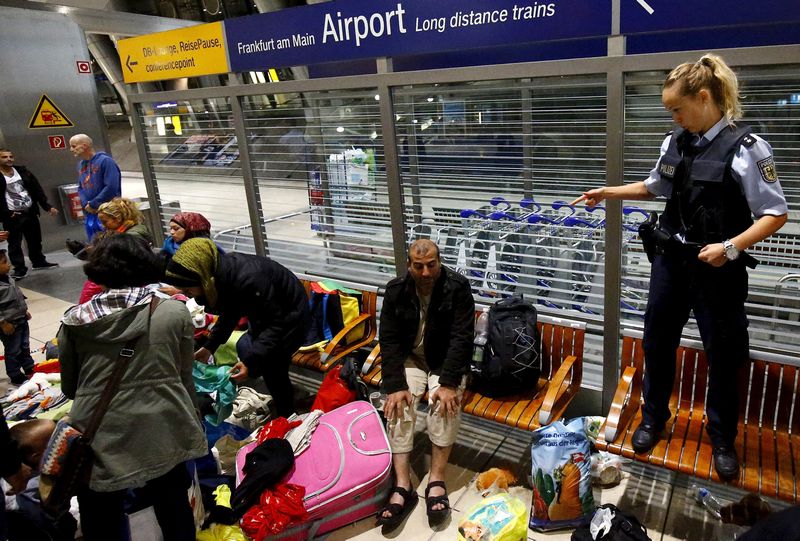 A German border policewoman stands on a bench while talking to migrants at the railway station of the airport in Frankfurt, early morning of September 6, 2015. u00e2u20acu201d Reuters pic