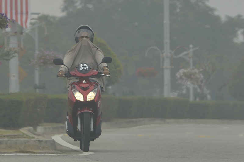 A motorcyclist covers his mouth and nose with his jacket due to the haze, in Putrajaya, Sept. 11, 2015. Putrajaya recorded an unhealthy API level of 103 as at 5pm. u00e2u20acu201d Bernama pic