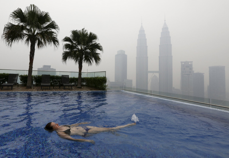A woman swims in a rooftop pool in front of the Petronas Towers, shrouded by haze, in Kuala Lumpur, September 13, 2015. u00e2u20acu201d Reuters pic