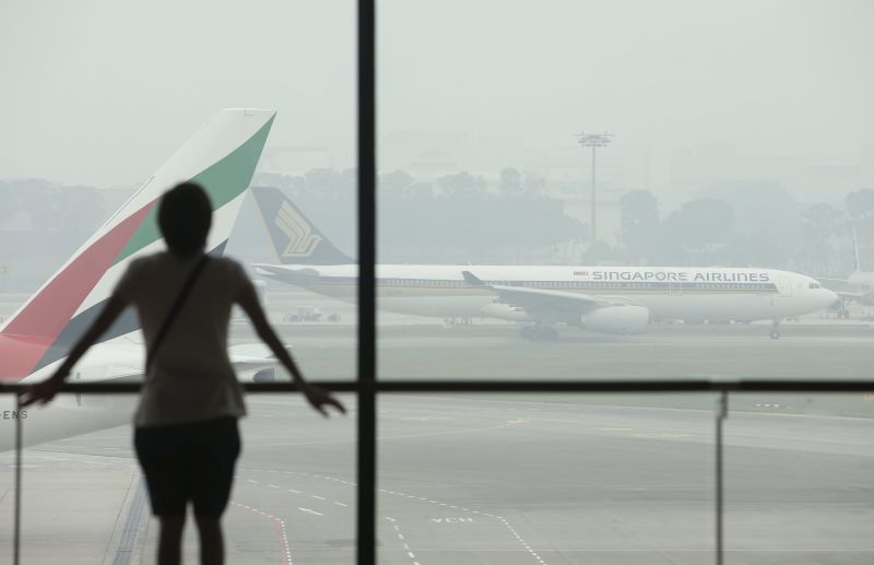 A woman watches as a Singapore Airlines plane prepares to take off, from a viewing gallery in Singapore's Changi Airport September 29, 2015. u00e2u20acu201d Reuters pic