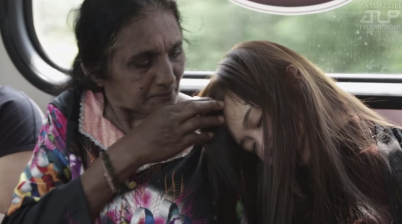 An elderly lady gently brushed the hair off the face of the female actress who pretended to fall asleep on her shoulder in this screenshot from the video by Jason Lim Productions.