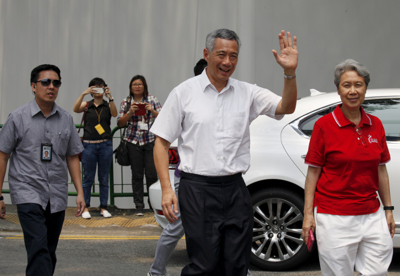 Singapore’s Prime Minister and Secretary-General of the People’s Action Party Lee Hsien Loong (second left) and his wife Ho Ching (right) arrive to cast their votes at a polling centre in Singapore September 11, 2015. — Reuters pic