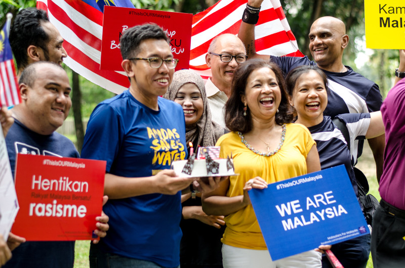 Datin Paduka Marina Mahathir and other participants hold a cake, placard and the Malaysian flag to commemorate Malaysia Day at a picnic to celebrate the event, September 16, 2015. u00e2u20acu201d Picture by Ida Lim