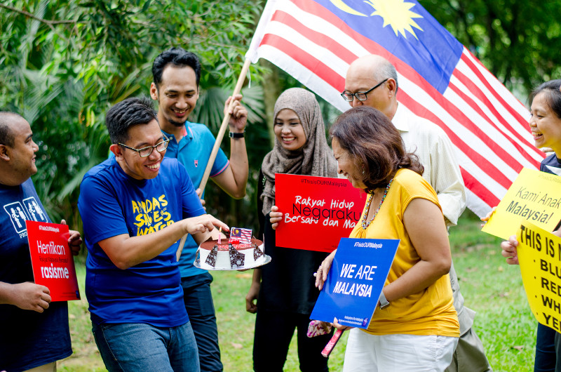 Datin Paduka Marina Mahathir and other participants hold a cake, placard and the Malaysian flag to commemorate Malaysia Day at a picnic to celebrate the event, September 16, 2015.