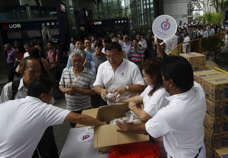 Volunteers distribute fans, water, pens and clappers to people attending the lunchtime rally by the ruling People's Action Party (PAP) at the central business district in Singapore September 8, 2015. u00e2u20acu201d Reuters pic