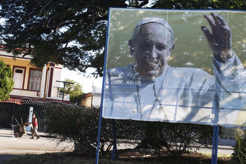 A street sweeper walks near a sign with a photograph of Pope Francis in Havana September 19, 2015. u00e2u20acu201d Reuters pic