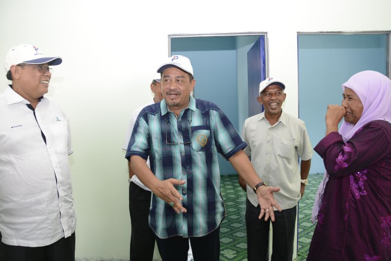 Puan Ruzaini sharing sentiments on her new house with Galas ADUN, YB Abdul Aziz Yusoff (centre, in blue shirt) and Datuk Sri Muzaffar Syah, Managing Director of Maintenance and Construction Divisions.