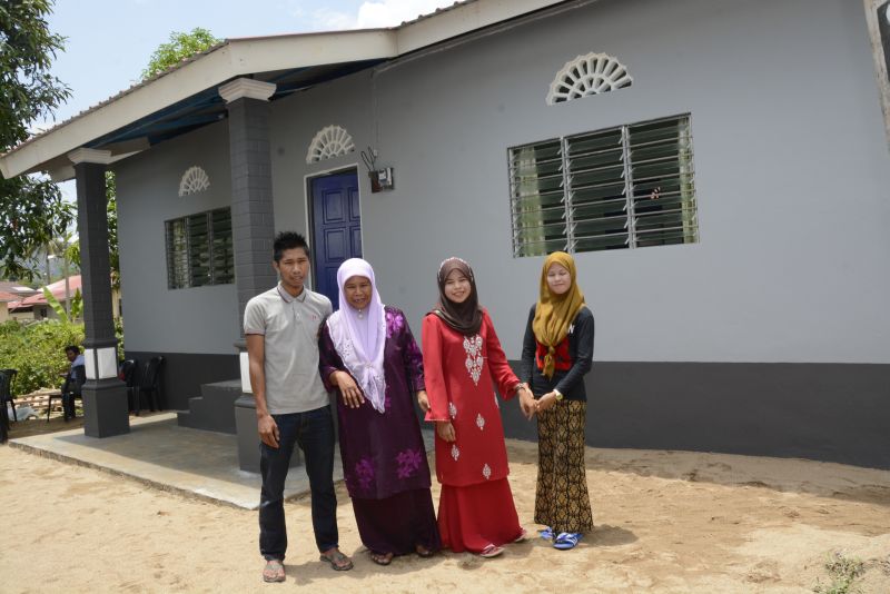 Single mum, Puan Ruzaini bt Abdullah (in purple tudung) and her children in front of their new house, presented by Protasco and Roadcare (M) Sdn Bhd.