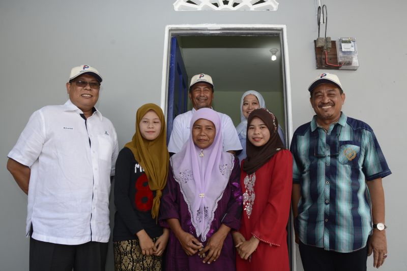 Puan Ruzaini (centre in purple tudung) and her daughters (second and fourth left in front row) are happy to receive their new home, a CSR initiative by Protasco and Roadcare.