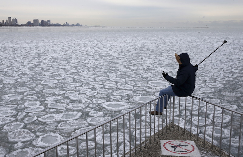 A man sits on a railing to take a u00e2u20acu02dcselfieu00e2u20acu2122 picture, overlooking the partially frozen Lake Michigan in Chicago, Illinois, in this January 5, 2015 file photo. u00e2u20acu201d Reuters pic