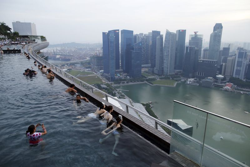 Tourists look out into the skyline of the city from an infinity pool atop the 57-storey-high Marina Bay Sands hotel in Singapore July 10, 2015 