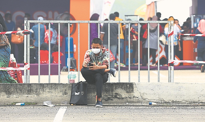 A man wears a mask while he sits at the roadside in Batu Kawan yesterday. Penang residents are snapping up face masks following the unhealthy Air Pollutant Index readings. u00e2u20acu201d Picture by Sayuti Zainudin