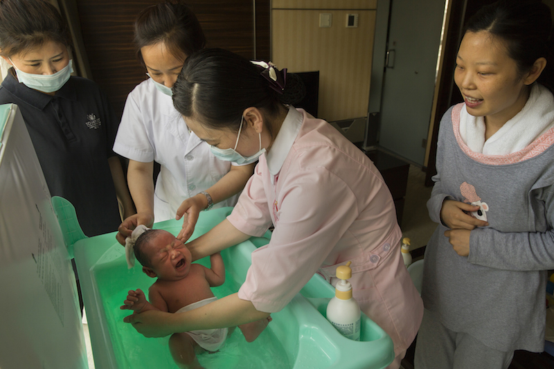 A nurse washes Lei Yaoran, Li Rui’s, right, new baby, before he is massaged at the Red Wall Mother and Baby Care Centre in Beijing May 29, 2015. — Picture Adam Dean/The New York Times