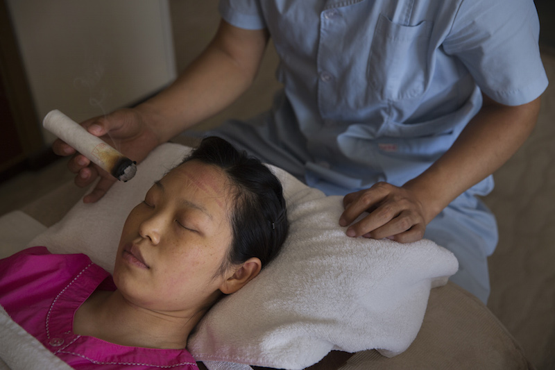 A therapist gives new mother Li Rui a moxibustion treatment — with smoking sticks of mugwort — at the Red Wall Mother and Baby Care Centre in Beijing May 29, 2015. — Picture Adam Dean/The New York Times