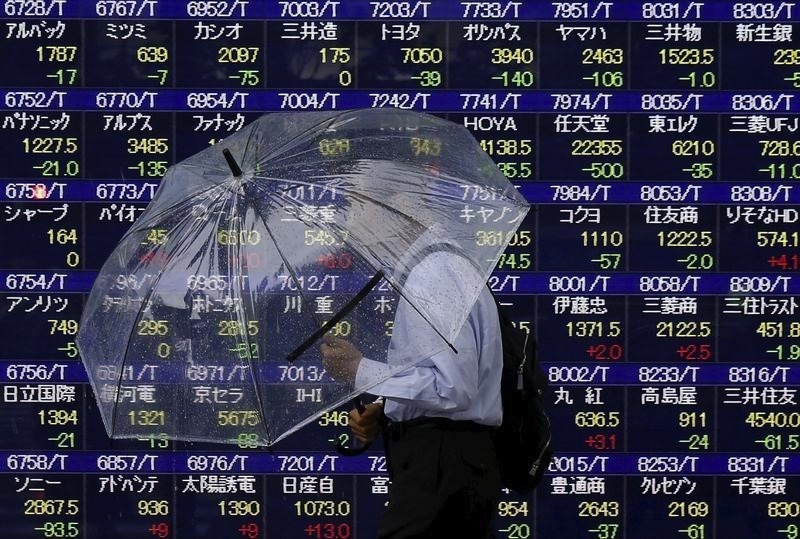 A man holding an umbrella walks in front of an electronic stock quotation board outside a brokerage in Tokyo September 8, 2015. u00e2u20acu201d Reuters pic