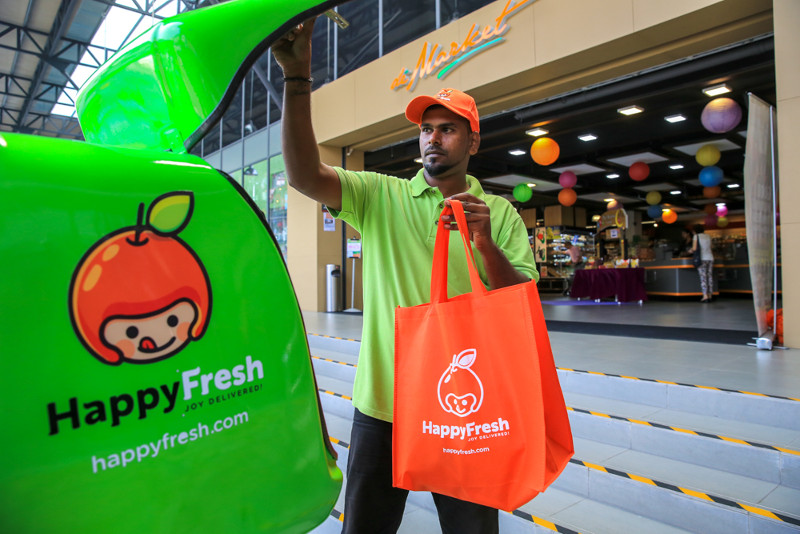 Happy Fresh driver loading up groceries into delivery box, to be sent to customers. u00e2u20acu201d Picture by Saw Siow Feng