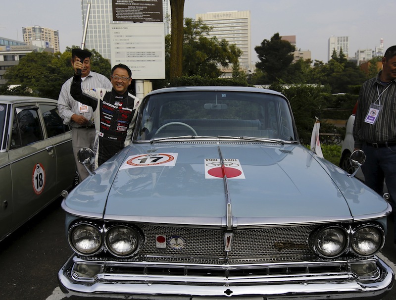 Akio Toyoda holds a torch for the 1964 Tokyo Olympics as he poses with the Prince Gloria DX Official 1964 Tokyo Olympic Car after a parade to promote next week's Tokyo Motor Show in Tokyo, Japan October 24, 2015. u00e2u20acu201d Reuters pic