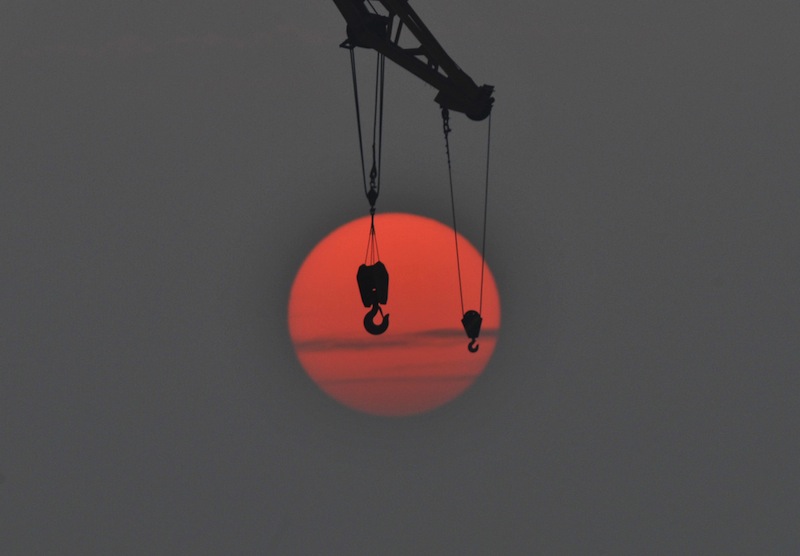 The hooks of a crane are pictured in front of the setting sun, at a port in Qingdao, Shandong province, China, October 14, 2015. u00e2u20acu201d Reuters pic