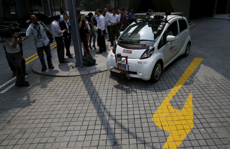 Members of the media watch as an autonomous self-driving vehicle goes onto the road during a demonstration at One North business park, unveiled in Singapore October 12, 2015. REUTERS/Edgar Su