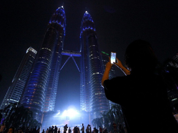 A tourist uses a smart phone to take pictures of the Petronas Twin Towers that glittered in blue light last night. The iconic Kuala Lumpur landmark was lit in blue to mark the 70th anniversary of the United Nations (UN) in New York. u00e2u20acu201d Bernama pic