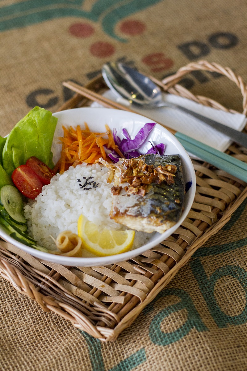 Grilled mackerel rice at Await Café, drizzled with burnt garlic oil and served with Japanese rice, fresh vegetables, lemon and pickles. 