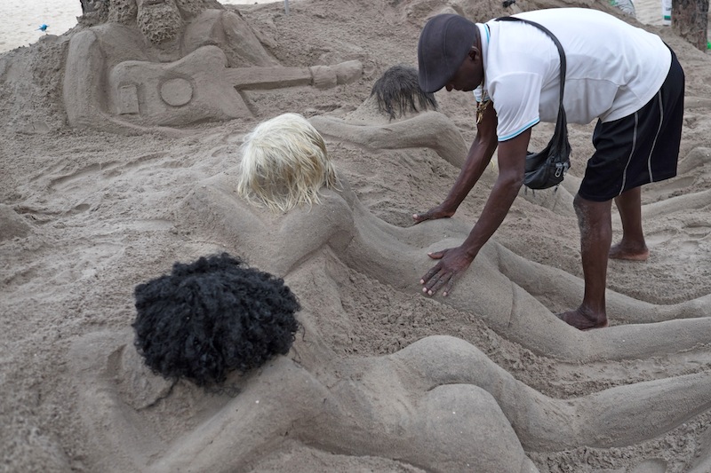 Ubiratan da Conceiu00c3u00a7ao dos Santos, who has created sand sculptures of women at Copacabana beach for 23 years, touches one of his creations in Rio de Janeiro, Brazil on December 2, 2015. u00e2u20acu201d AFP pic