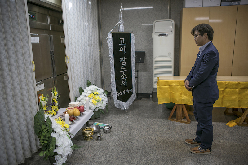 Park Jin-ok, executive director and social worker for Good Nanum, pays a silent tribute in front of a refrigerator of a morgue where an unclaimed body was kept in Seoul September 24, 2015. u00e2u20acu201d Picture by Jean Chung/The New York Times