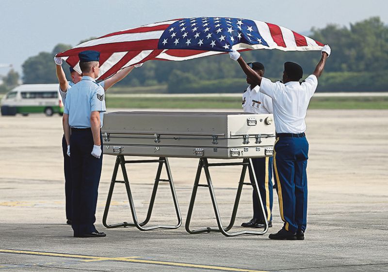 US soldiers drape the Star Spangled Banner on a casket containing the remains of one of the WWII airmen during the handing over ceremony at the Royal Malaysian Air Force base in Subang yesterday. u00e2u20acu201d Picture by Zuraneeza Zulkifli