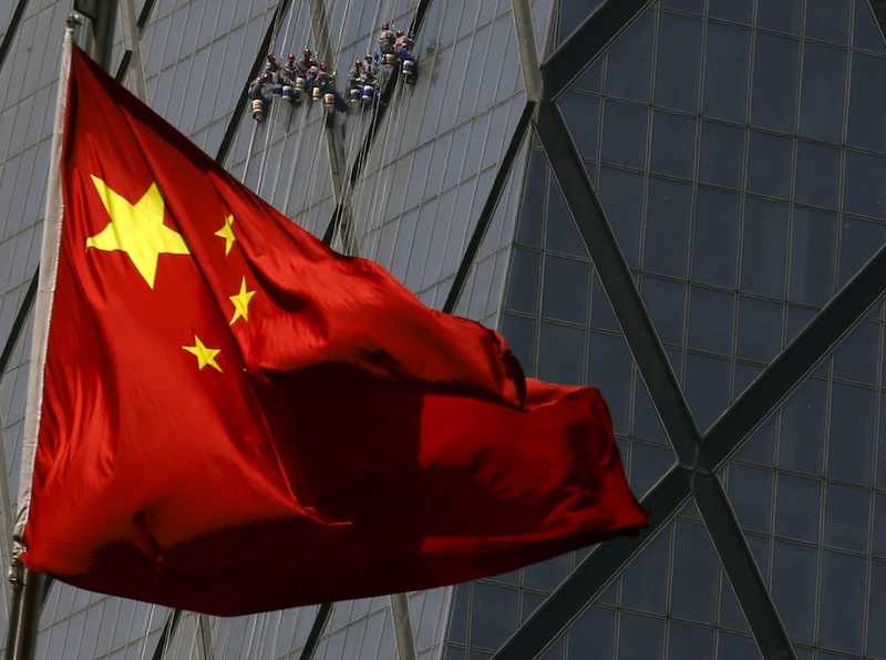 Workers cleaning windows of a building are seen behind China's national flag at a commercial district in Beijing in this April 20, 2015 file photo. u00e2u20acu201d Reuters pic