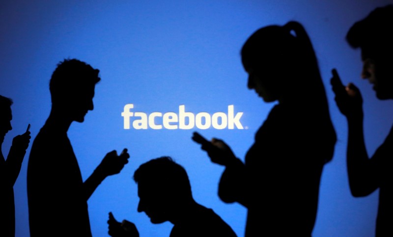 People are silhouetted as they pose with mobile devices in front of a screen projected with a Facebook logo, in this picture illustration. u00e2u20acu201d Reuters pic