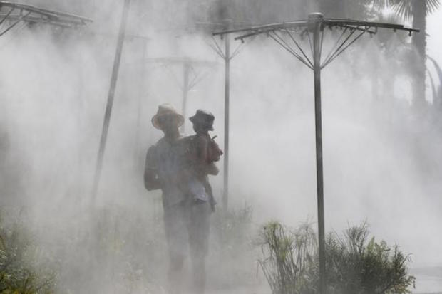A man and his child walk through a mist fountain on the banks of the river Seine as summer temperatures hit Paris August 12, 2015. u00e2u20acu201d Reuters pic