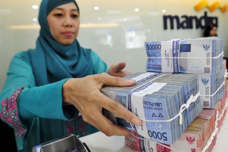 A teller at a Bank Mandiri branch handles Indonesian Rupiah currency during a transaction in Jakarta July 20, 2015 in this file photo taken by Antara Foto. u00e2u20acu201d Reuters pic