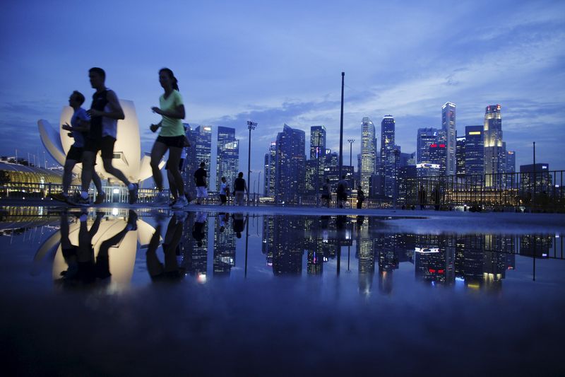 Joggers run past as the skyline of Singapore's financial district is seen in the background in this April 21, 2014 file photo. Singapore's Straits Times Index fell after the government softened its 2015 outlook. u00e2u20acu201d Reuters pic 