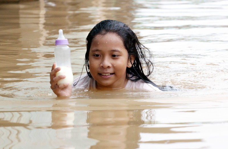 Waheeda Umairah Nik Hassan has to swim to get a bottle of milk for her brother after their house was flooded due to the overflowing of Sungai Golok in Lubok Gong, Rantau Panjang, Kelantan, November 30, 2015. u00e2u20acu201d Bernama pic
