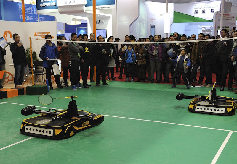 People look on as a robot (bottom L) plays badminton with a boy during a demonstration at the World Robot Conference in Beijing November 24, 2015. — Reuters pic