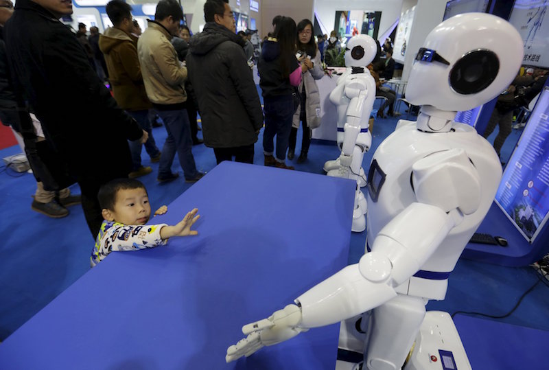 A boy gestures to a KINGER Robot at the World Robot Exhibition during the World Robot Conference in Beijing November 24, 2015. u00e2u20acu201d Reuters picn