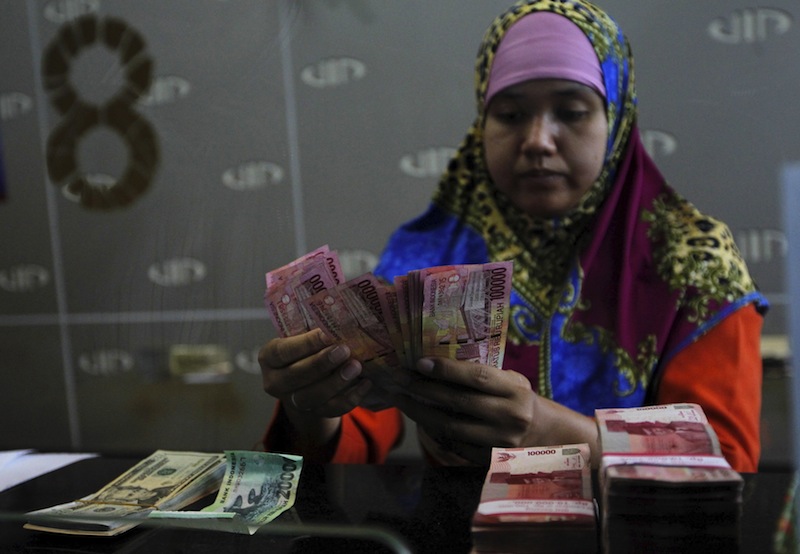 A teller counts Indonesian rupiah notes for a customer at a money changer in Jakarta, Indonesia, in this August 26, 2015 file photo. u00e2u20acu201d Reuters pic