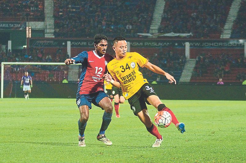 JDTu00e2u20acu2122s S. Kunanlan (left) and Sarawaku00e2u20acu2122s Tommy Mawat fight for the ball during their Malaysia Cup match on Saturday. The game ended 1-1. u00e2u20acu201d Picture by Nizam Rahman/asiana.my