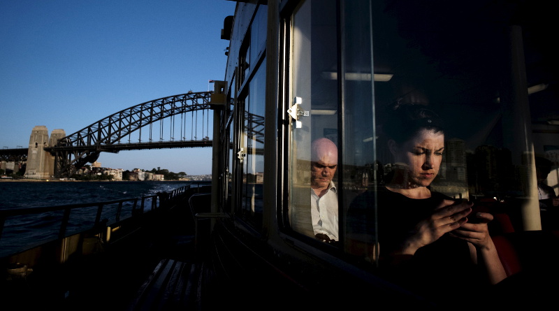A commuter uses her mobile phone as a Circular Quay to Cockatoo Island ferry passes under the Sydney Harbour Bridge, November 24, 2015. u00e2u20acu201d Jason Reed/Reuters pic