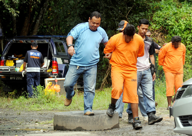 Two suspects (in orange shirt) in the murder of four individuals are brought to a vehicle repair workshop in Jalan Pahang, near Tapah to assist the police investigation, Nov 4, 2015. u00e2u20acu201d Bernama