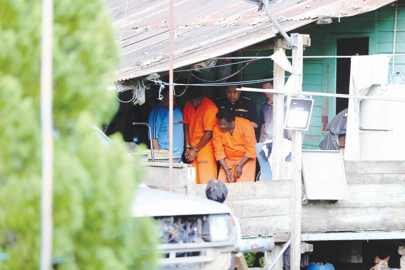 The suspects assist the police in gathering evidence at the shop-cum-house yesterday. u00e2u20acu201d Pictures by Farhan Najib