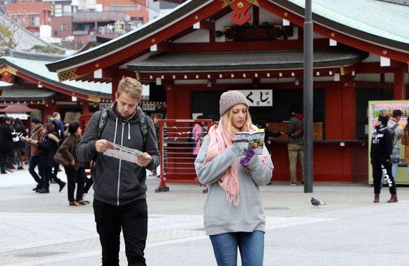 Foreign tourists look at a guidebook and a map at Sensoji temple at Tokyou00e2u20acu2122s Asakusa district March 3, 2015. u00e2u20acu201d AFP pic