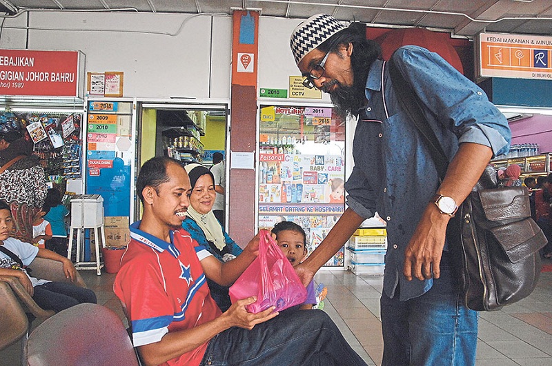 Zakaria (right) giving a packet of food to a caregiver at the hospital. u00e2u20acu201d Picture by Malay Mailn