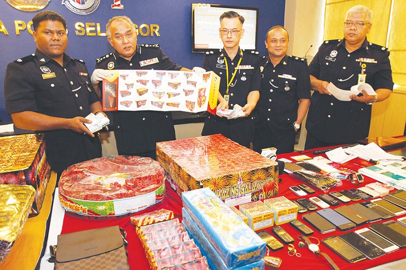 Selangor CID Chief Datuk Mohd Adnan Abdullah (second from left) displaying a catalogue of firecrackers which was among items seized in the raids in Klang. u00e2u20acu201d Picture by Sin Chew