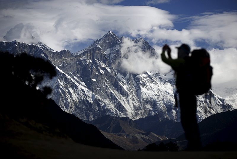 A tourist is silhouetted as he takes pictures of Mount Nuptse (centre) as Mount Everest (left) is covered with clouds in Solukhumbu district, also known as the Everest region, in this picture released December 20, 2015. — Reuters pic