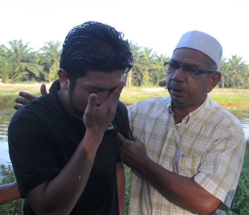 Ali Abdul Rahman (left), 28, mourns the loss of his family members who perished in the incident which took place at Sungai Bekok, Yong Peng on December 27, 2015. u00e2u20acu201d Bernama pic