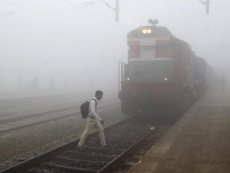A man crosses a railway track next to a stationed train on a foggy morning in Allahabad, India, December 7, 2015.u00c2u00a0u00e2u20acu201d Reuters pic