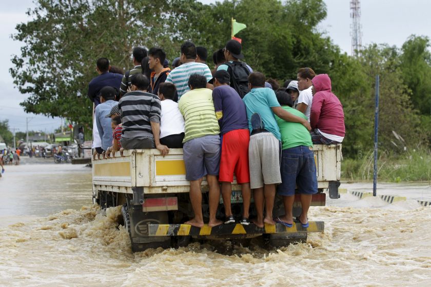 People ride on a delivery truck to cross a flooded road after heavy rain at Candaba town, Pampanga province, north of Manila, December 17, 2015. u00e2u20acu201d AFP pic